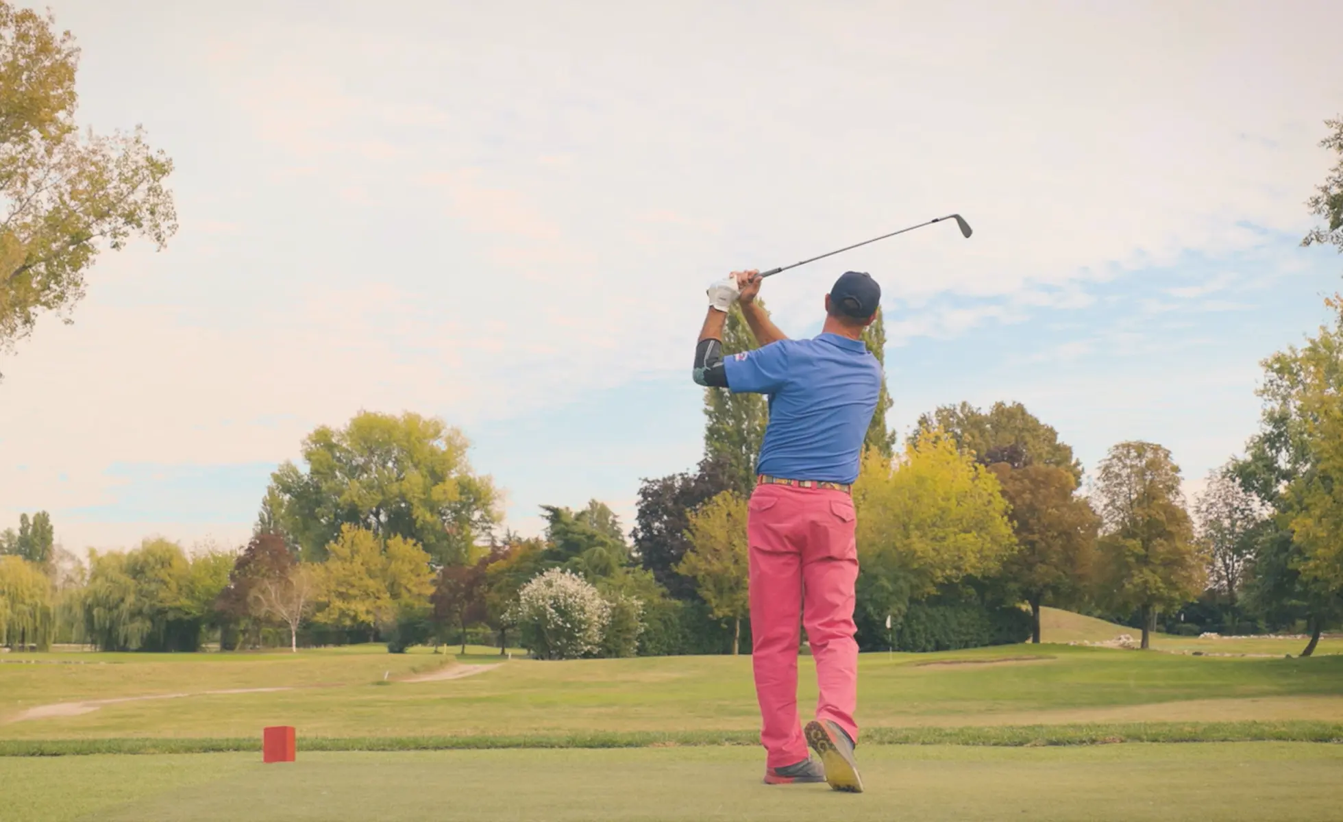 Golfista che ha appena colpito una pallina in un campo di erba sintetica a Milano