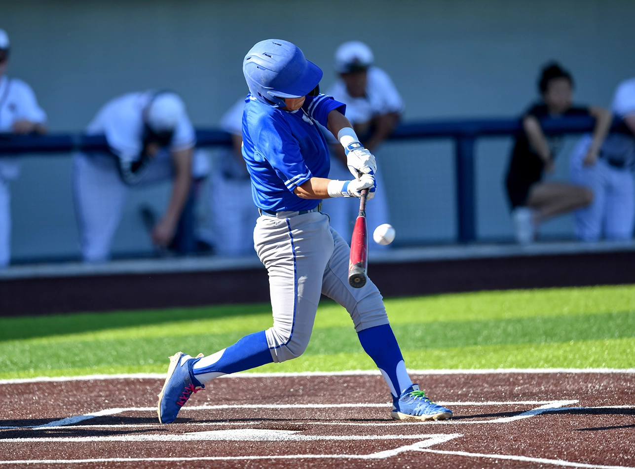 Giocatore di baseball che sta per colpire la palla in un campo di erba sintetica verde e marrone