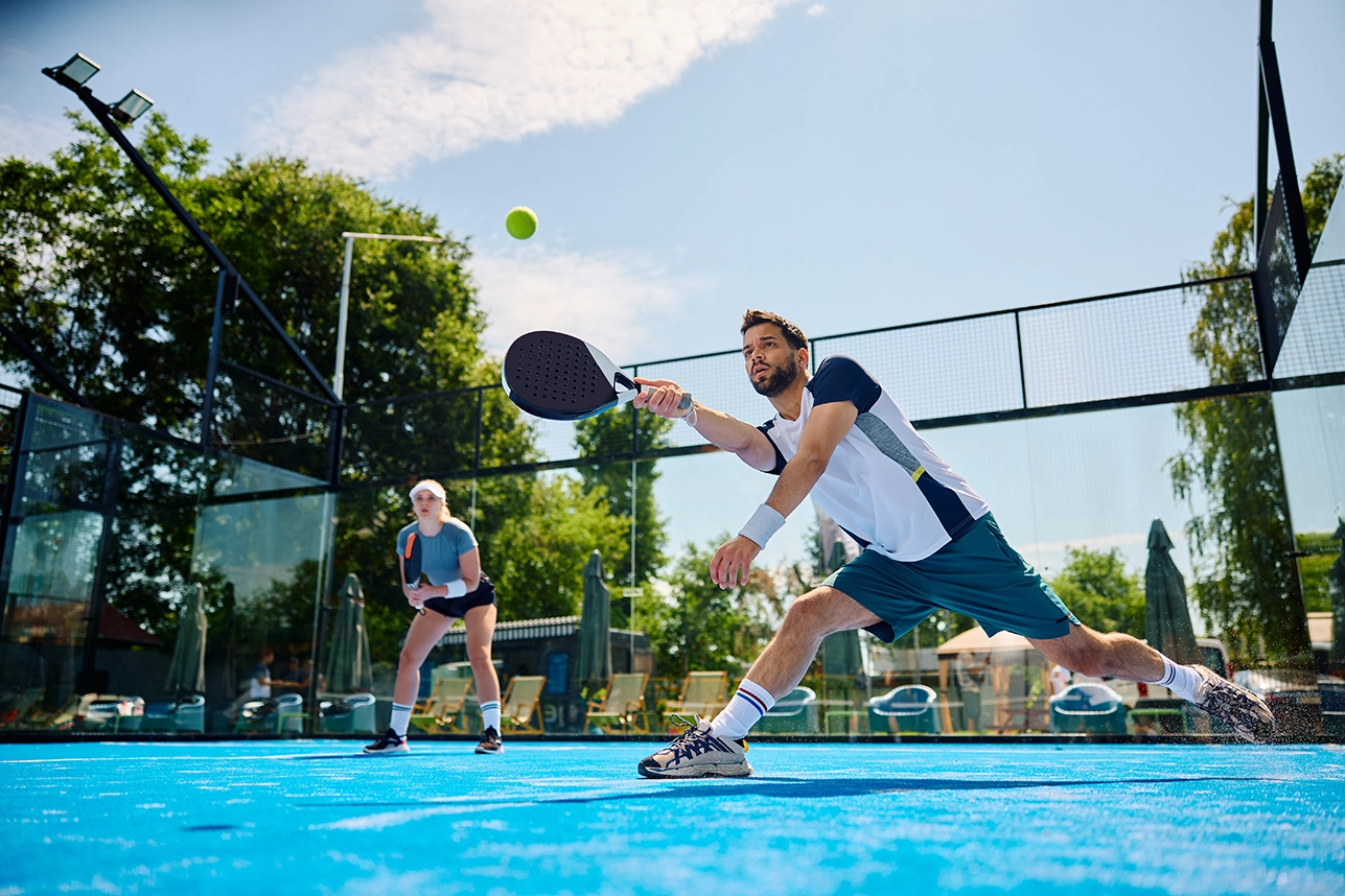 Persone che giocano a padel in un campo con erba sintetica blu