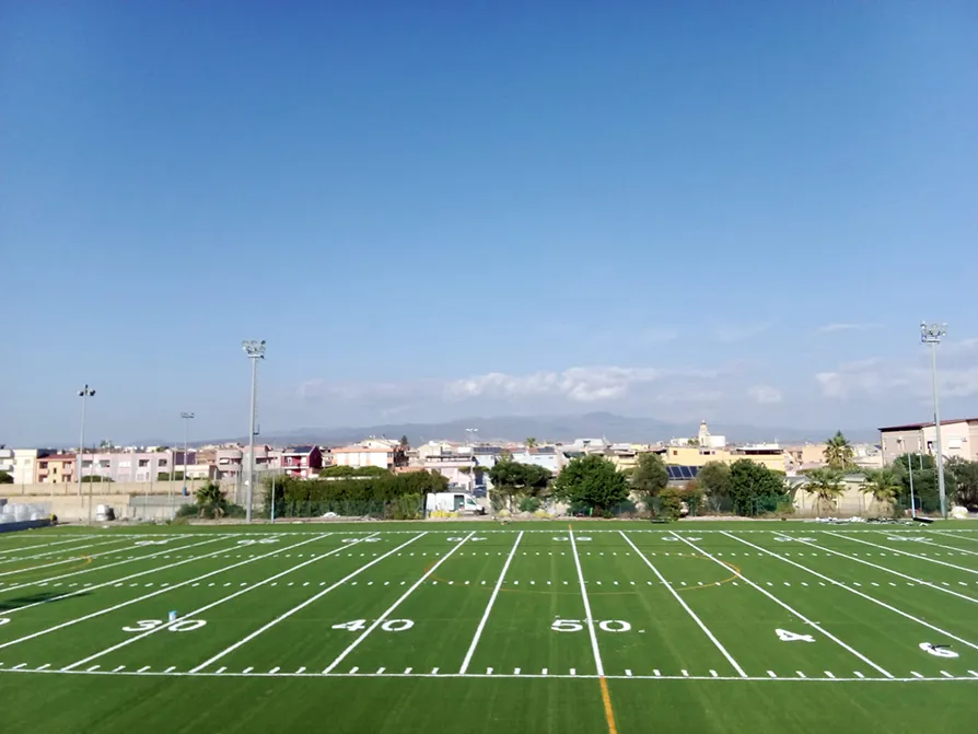 Campo di football americano a Cagliari visto lateralmente con erba sintetica.