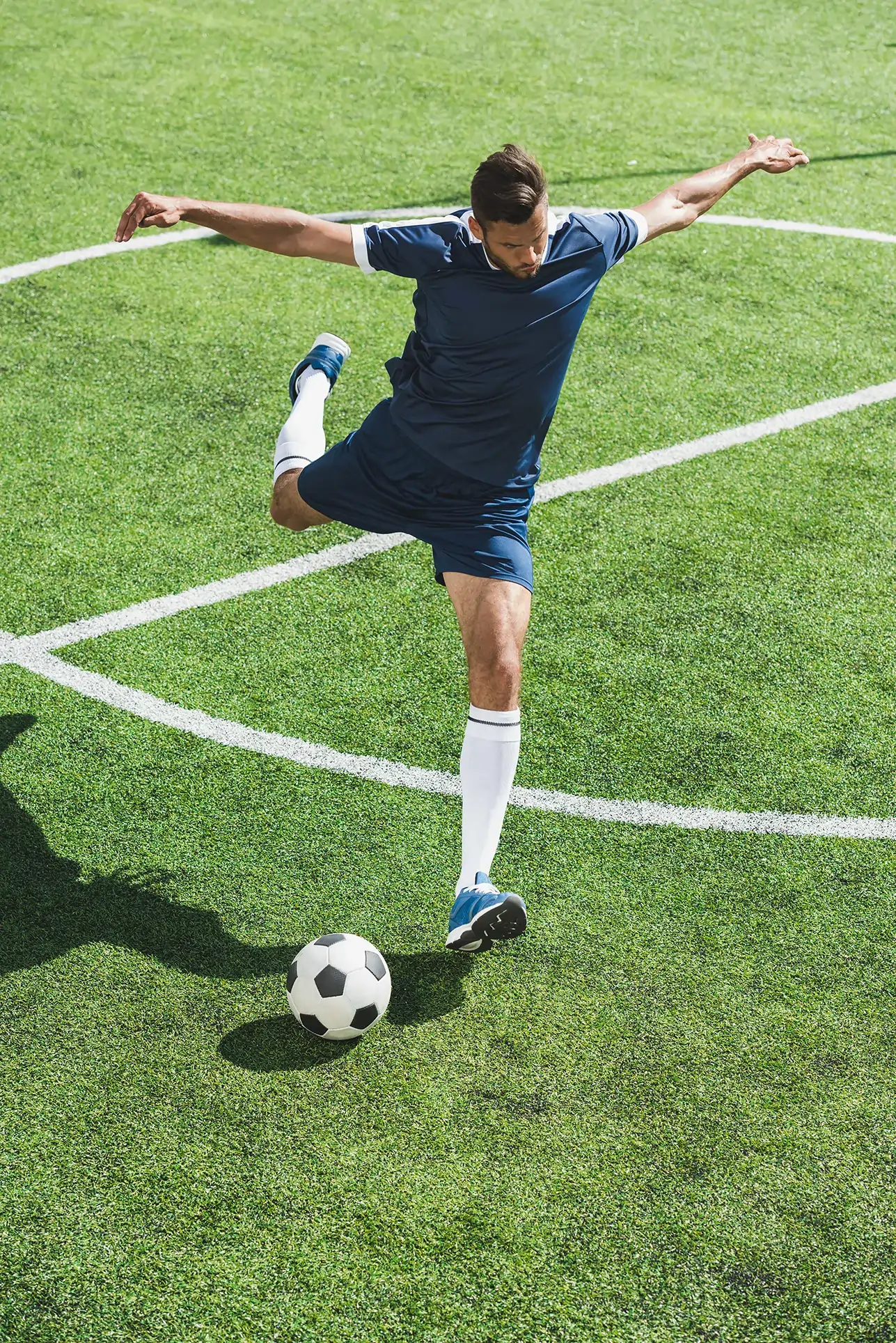 Calciatore che sta per calciare un pallone in un campo da calcio