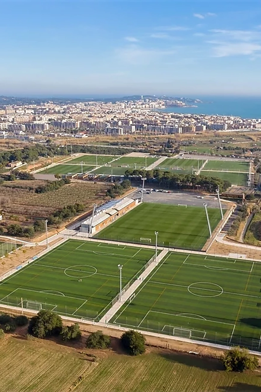 Vista dall'alto del complesso sportivo con campi composti da erba sintetica, vicino alla città.