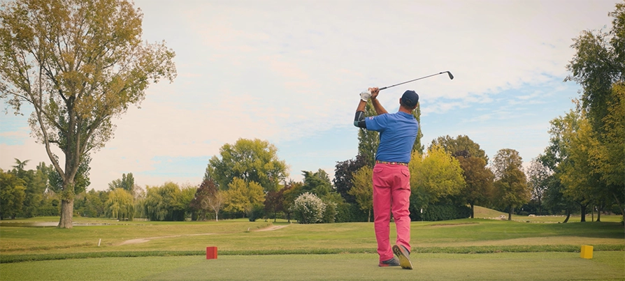 Golfista che ha appena colpito una pallina in un campo di erba sintetica a Milano