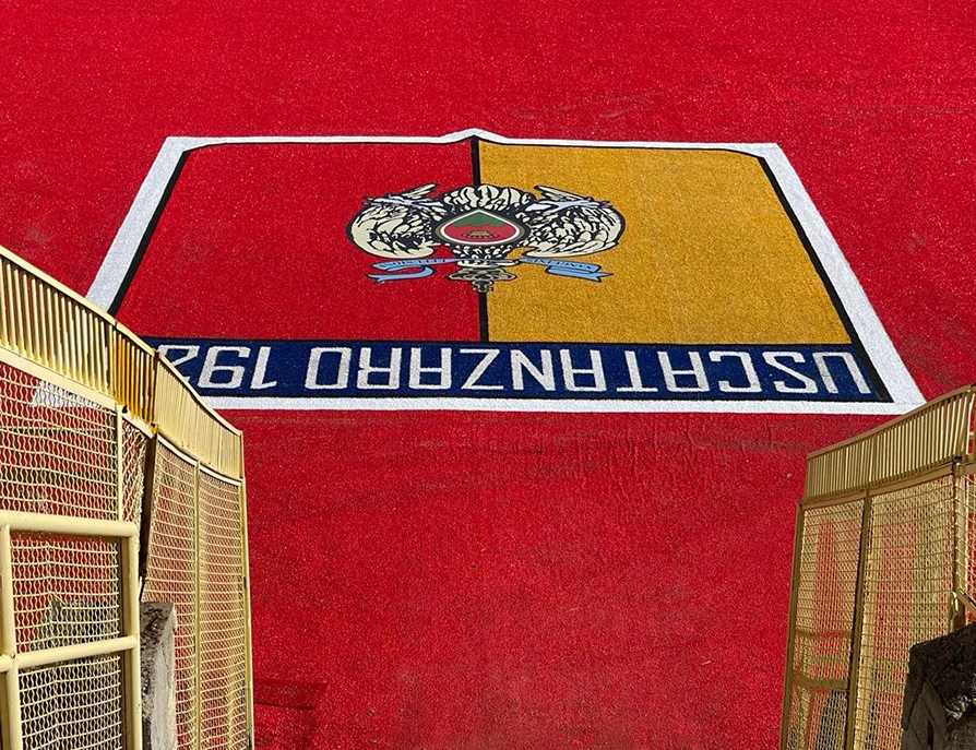 Logo dell'US Catanzaro composto da erba sintetica, vicino al rispettivo campo da calcio.