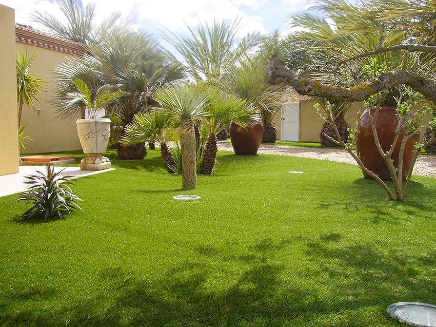 Villa privata con un giardino di erba sintetica con grandi vasi di piante e alberi