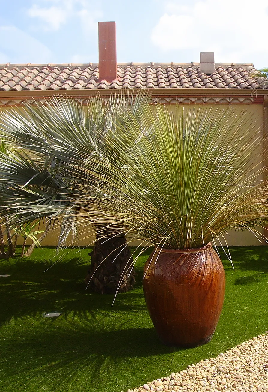 Giardino di una villa privata con vasi di piante sopra l'erba sintetica