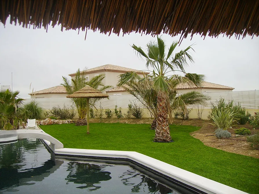 Giardino di una villa privata con piscina composto da erba sintetica.