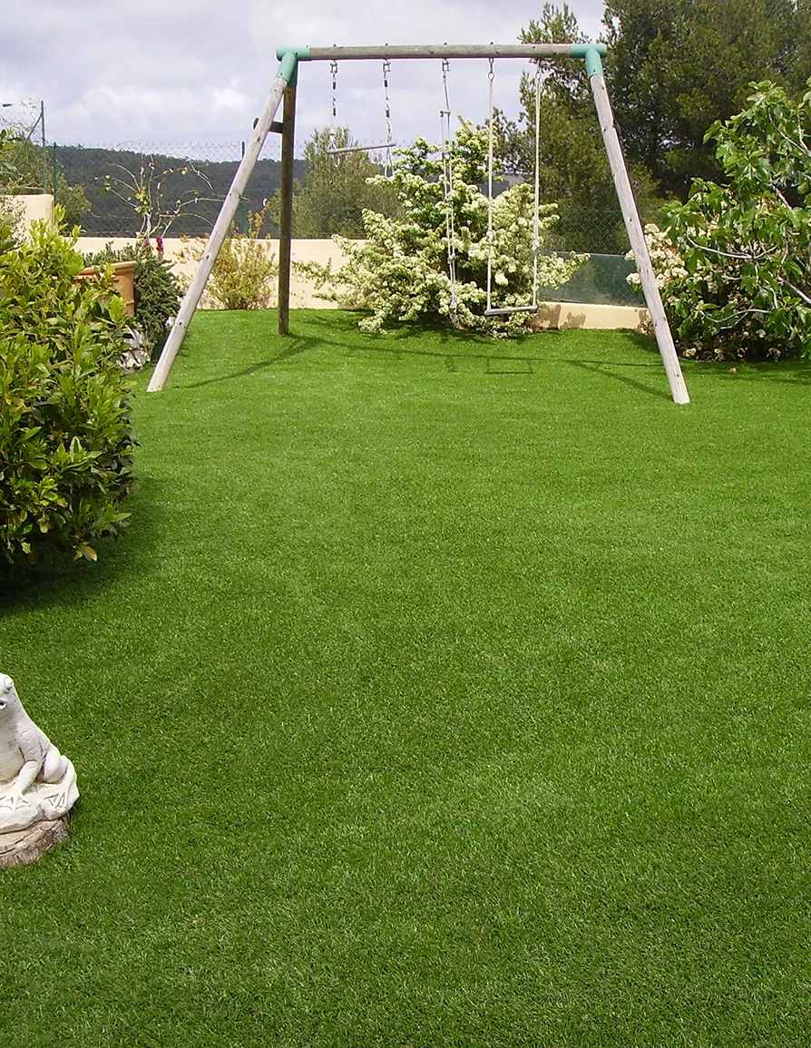 Giardino di una villa privata con erba sintetica vicino ad un altalena. 