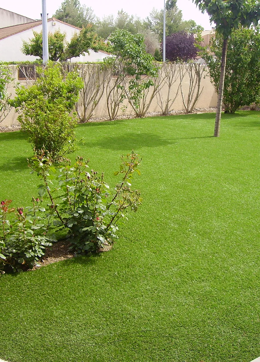 Giardino di erba sintetica con piante. 