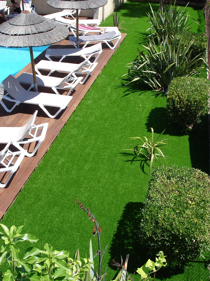 Erba sintetica in un giardino di una villa privata con piscina e ombrelloni, vista dall'alto